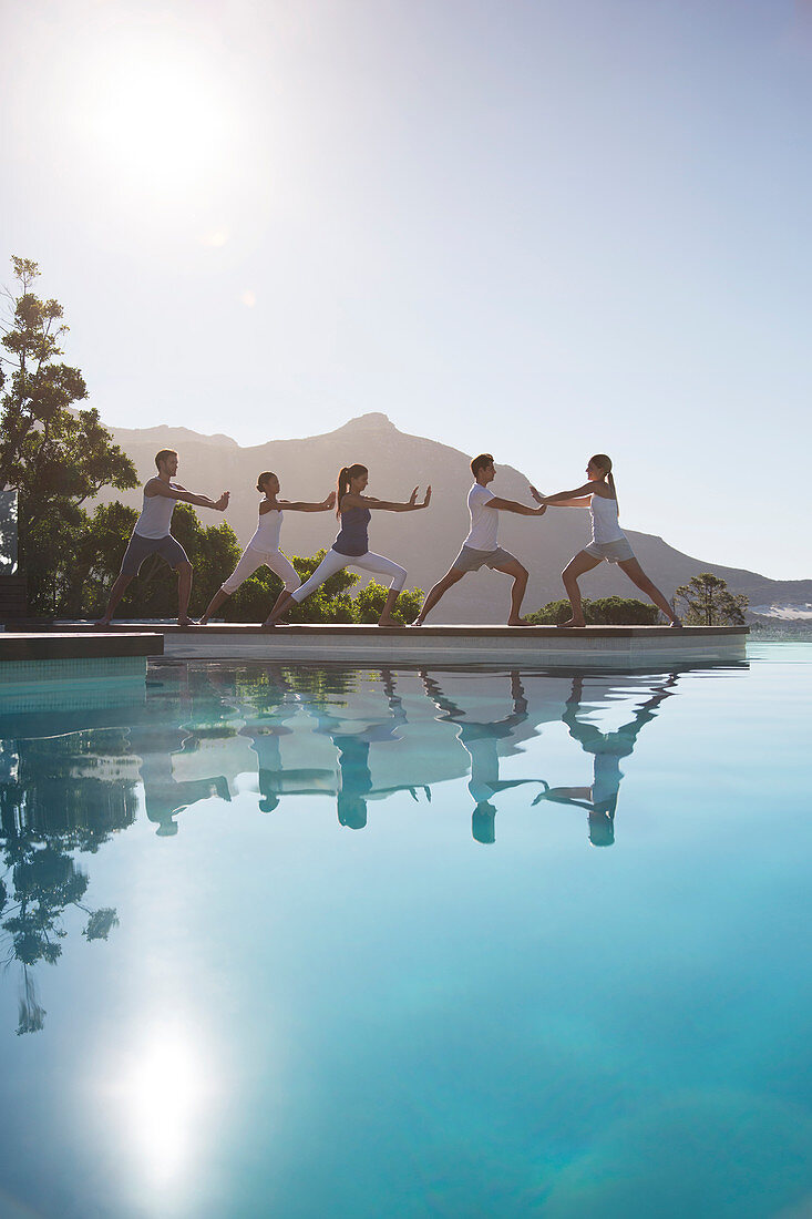 People practicing yoga at poolside