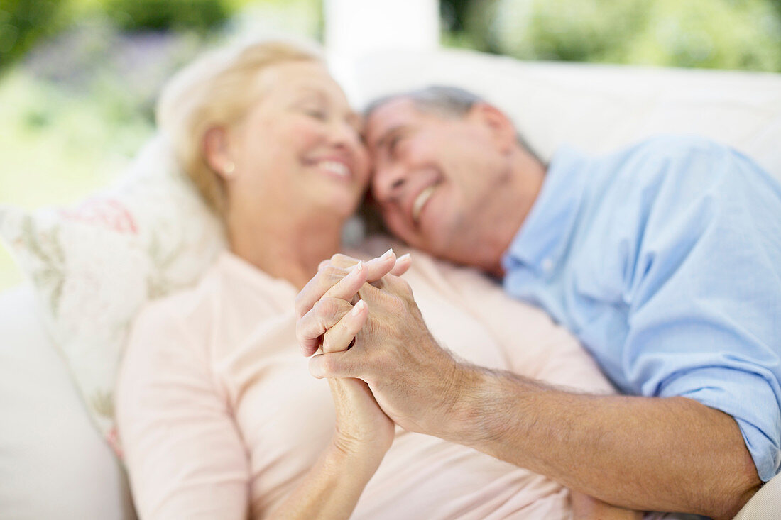 Senior couple holding hands on sofa