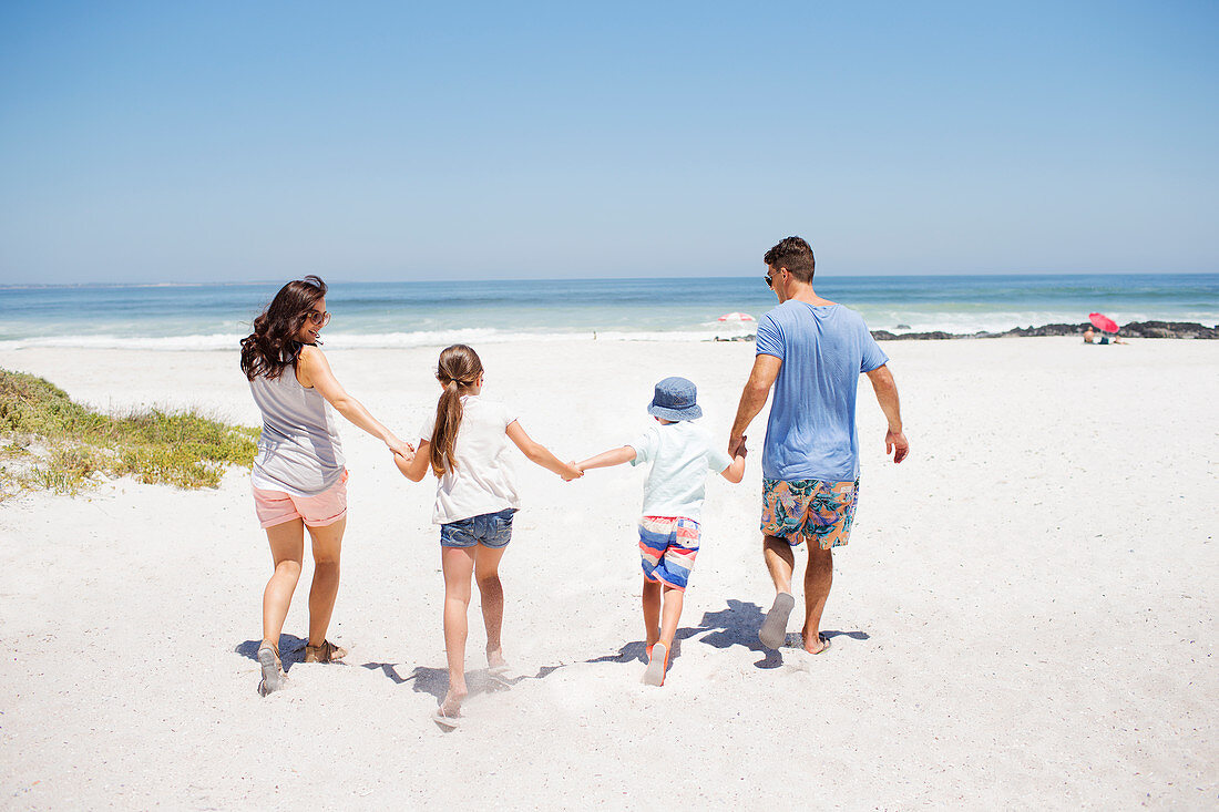 Family holding hands and walking on beach