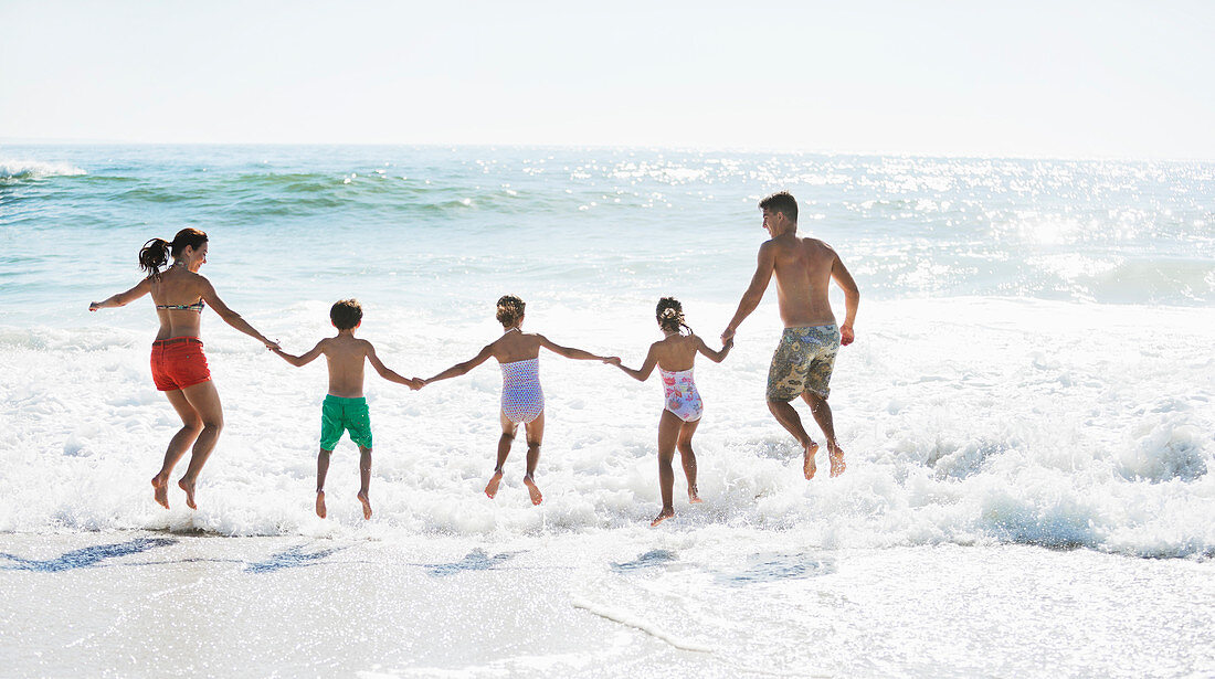 Family jumping in surf on beach