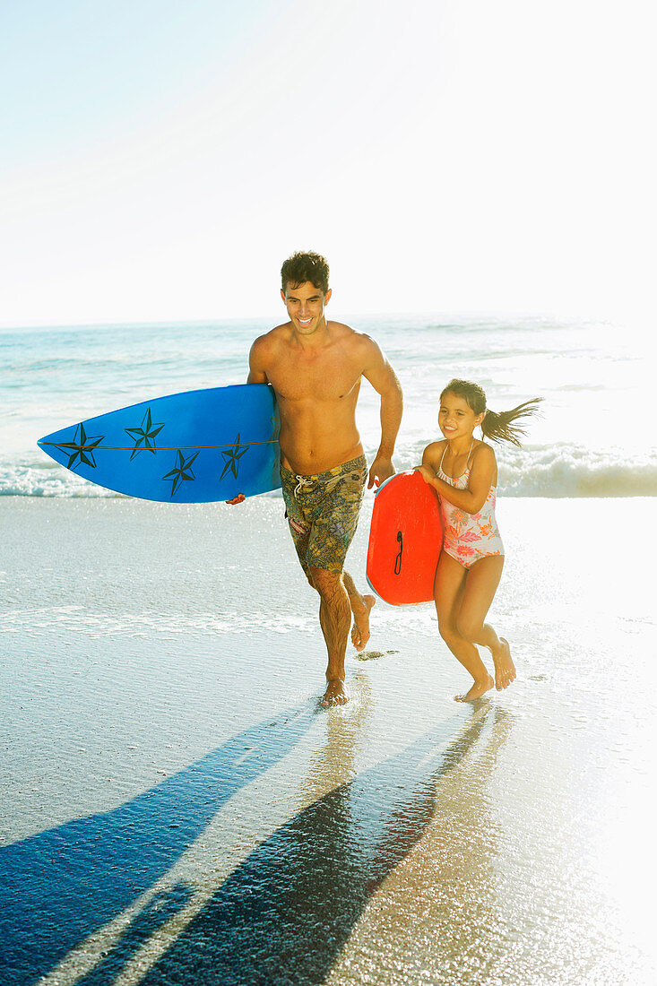 Father and daughter carrying surfboard