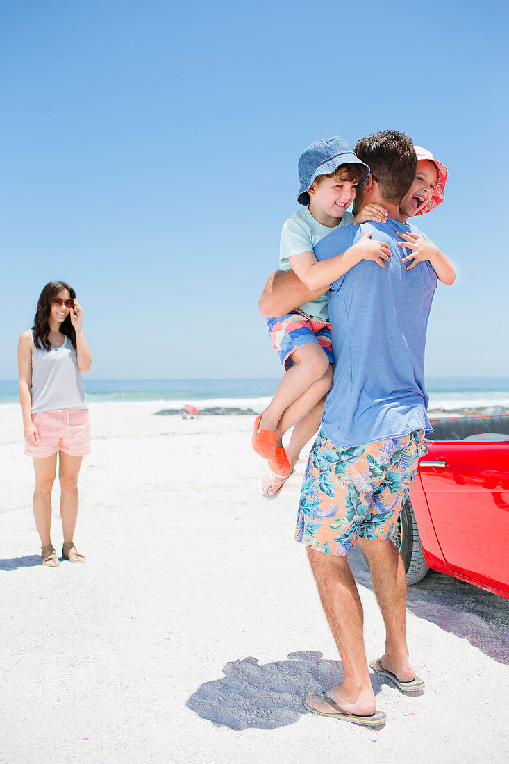 Father hugging children on beach