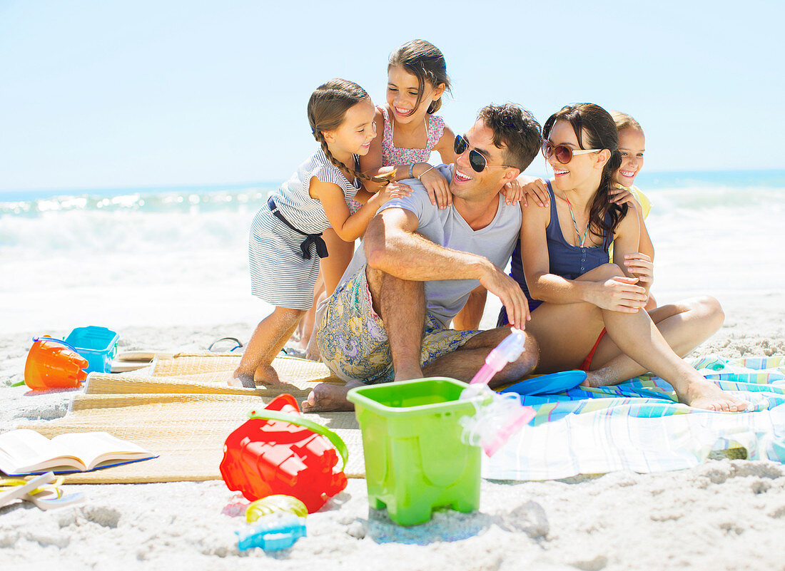 Family hugging on blanket at beach