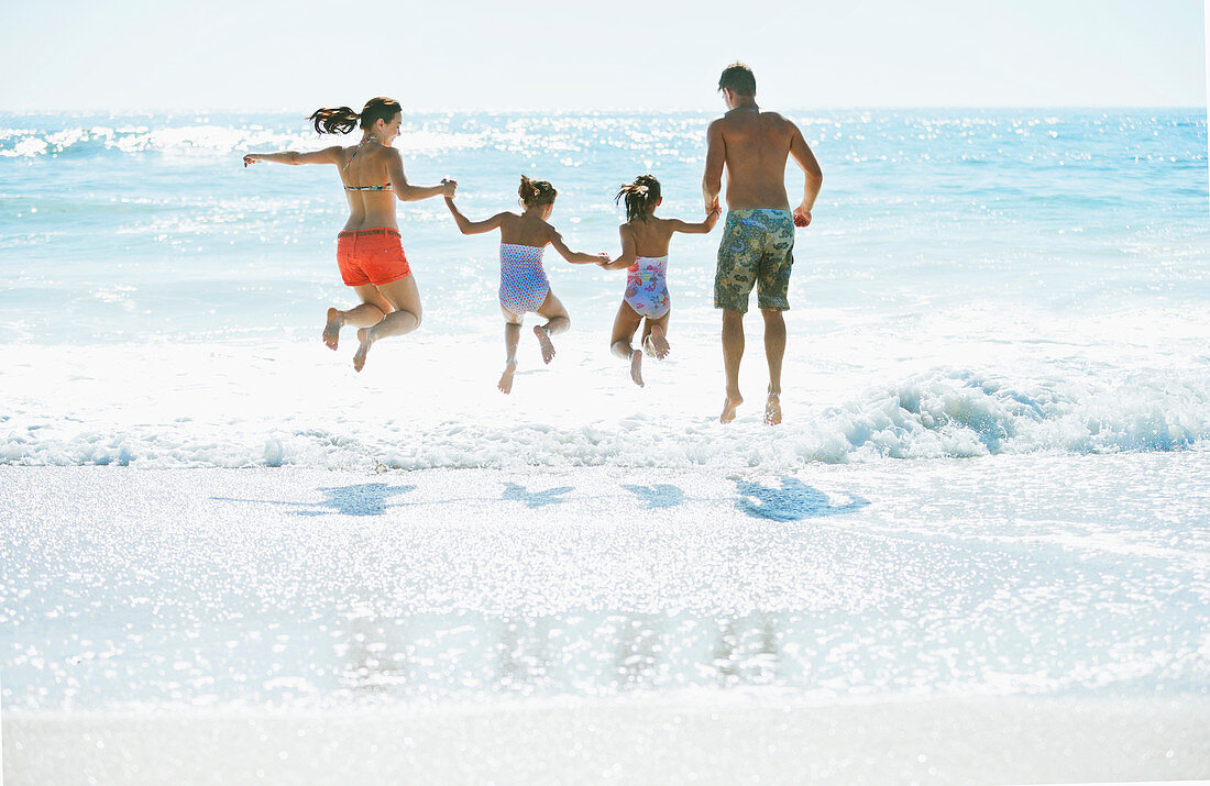 Family jumping in surf at beach