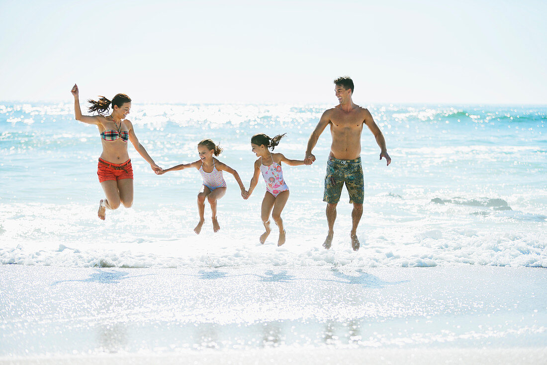 Family jumping in waves on beach