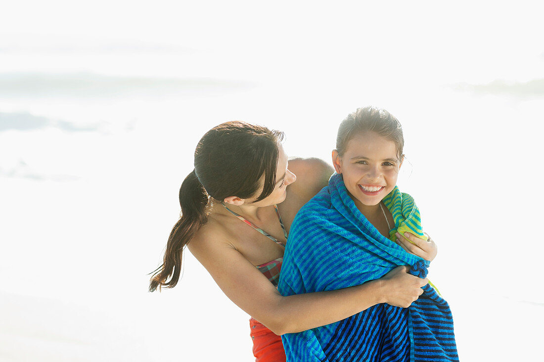 Mother wrapping daughter in towel