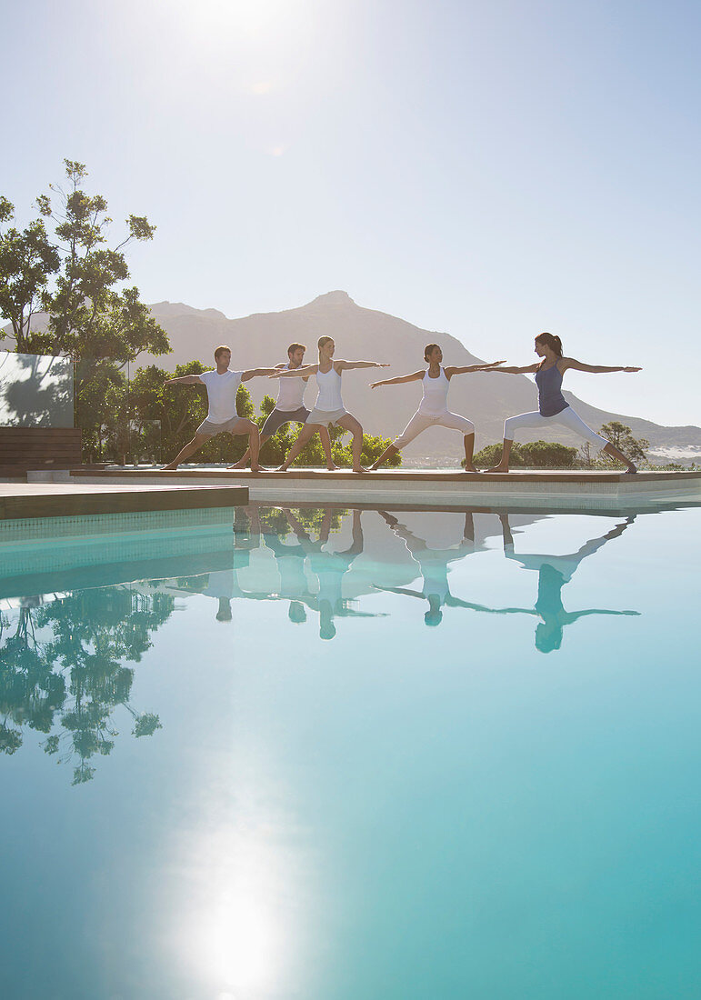 People practicing yoga at poolside