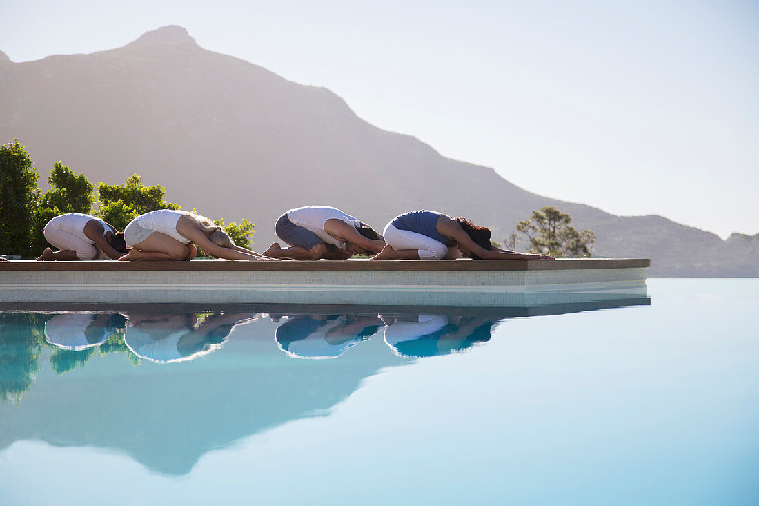 People practicing yoga at poolside