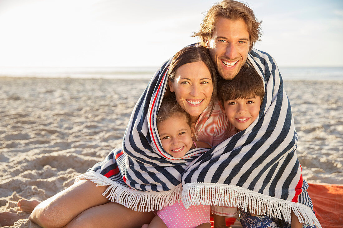 Family wrapped in blanket on beach