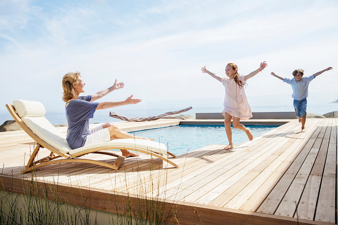 Children running to grandmother by pool