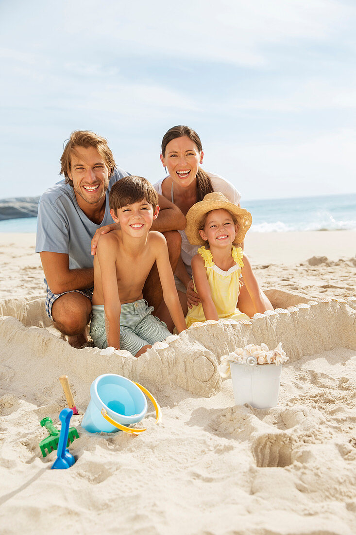 Family sitting in sandcastle on beach