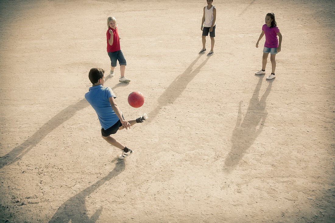 Children playing with soccer ball in sand