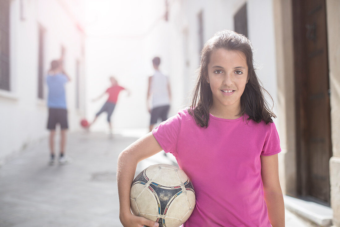 Girl holding soccer ball in alley
