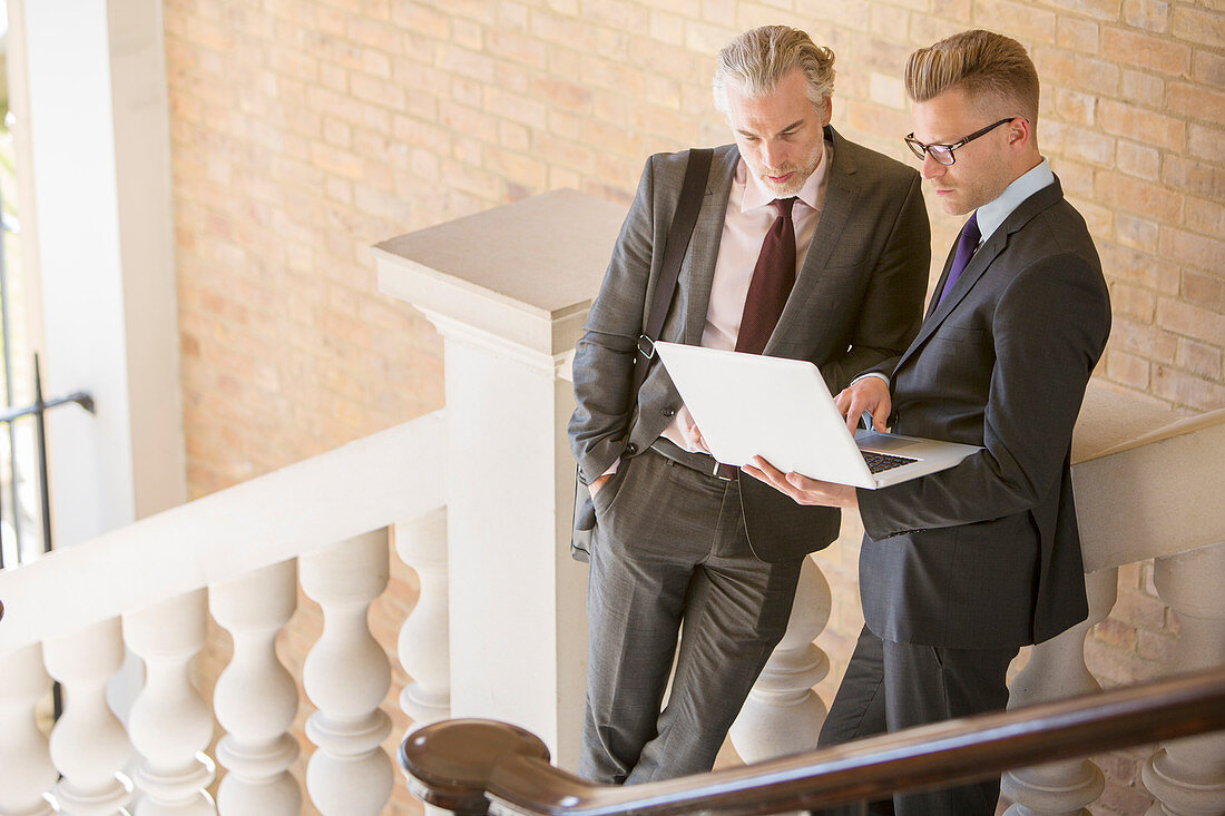 Businessmen using laptop on steps