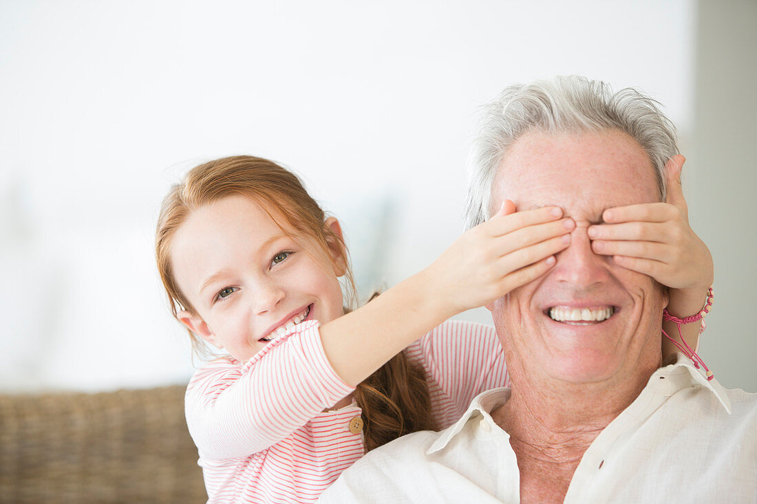 Girl covering grandfathers eyes