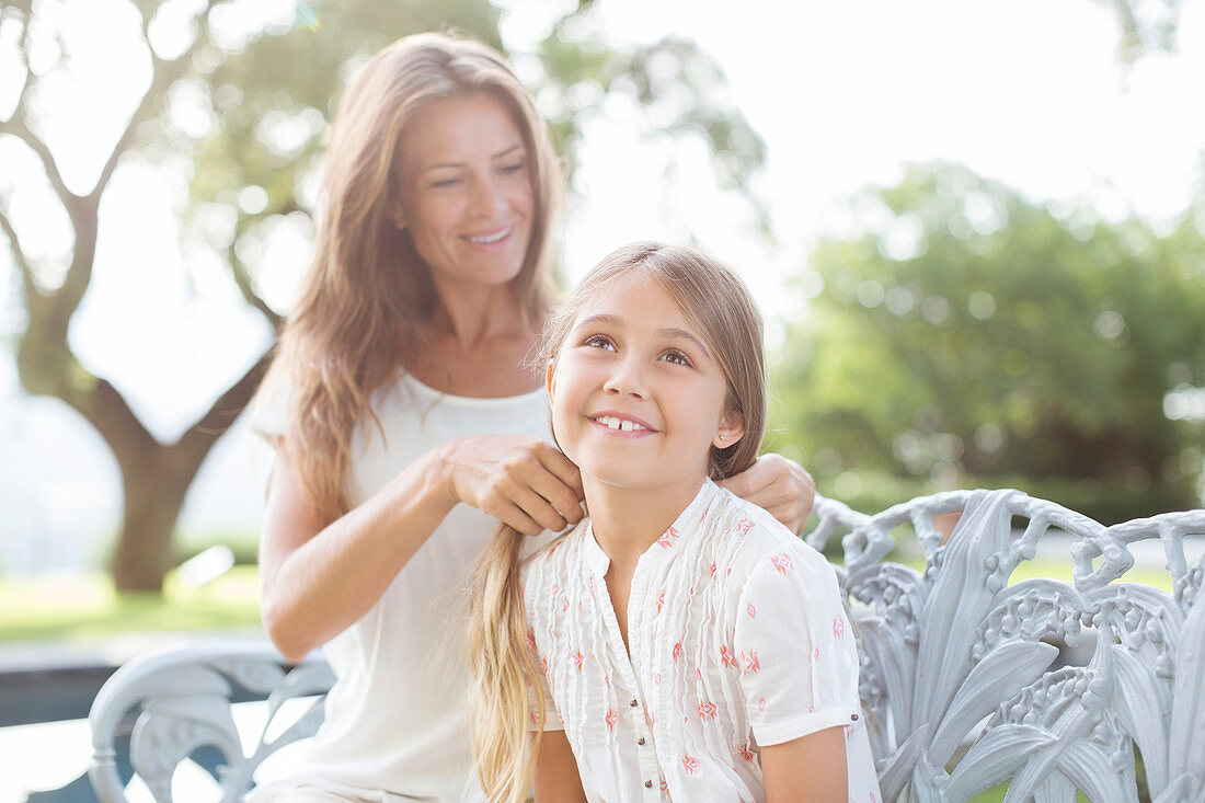 Mother braiding daughter's hair outdoors
