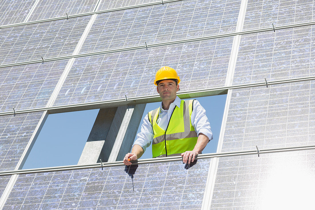 Worker examining solar panel