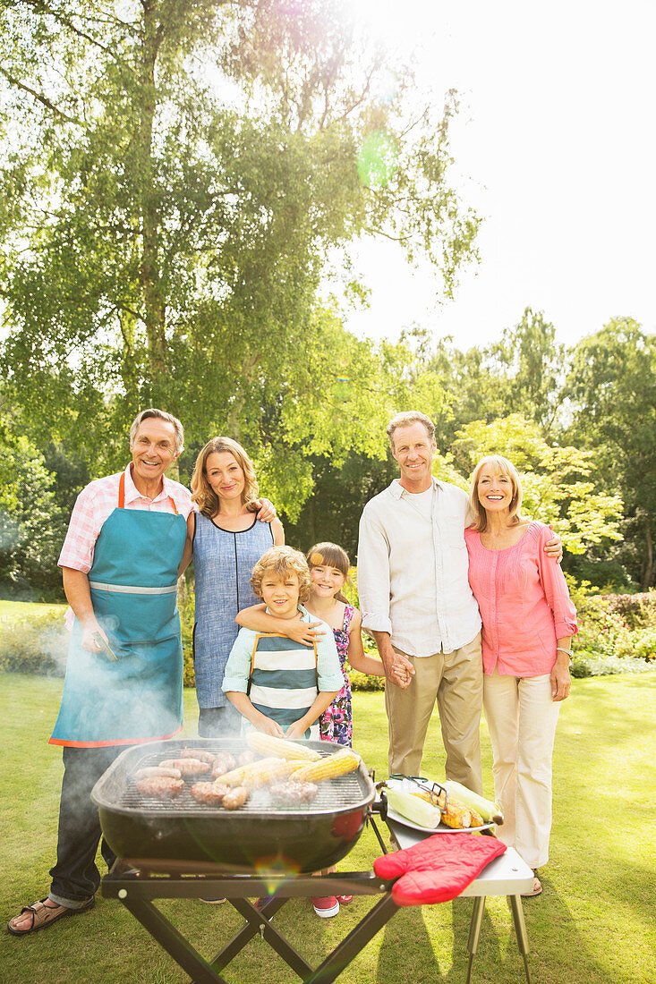 Family standing at barbecue in backyard