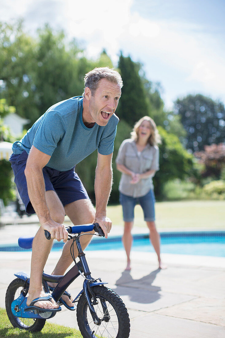 Man riding small bicycle at poolside