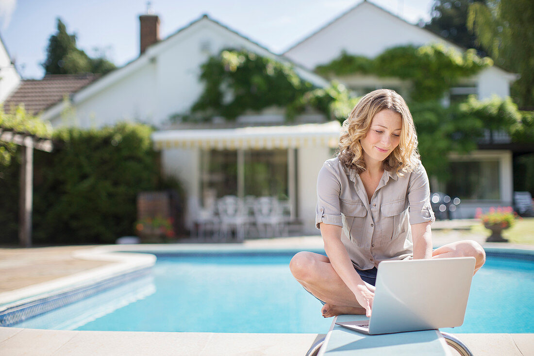 Woman using laptop on diving board side