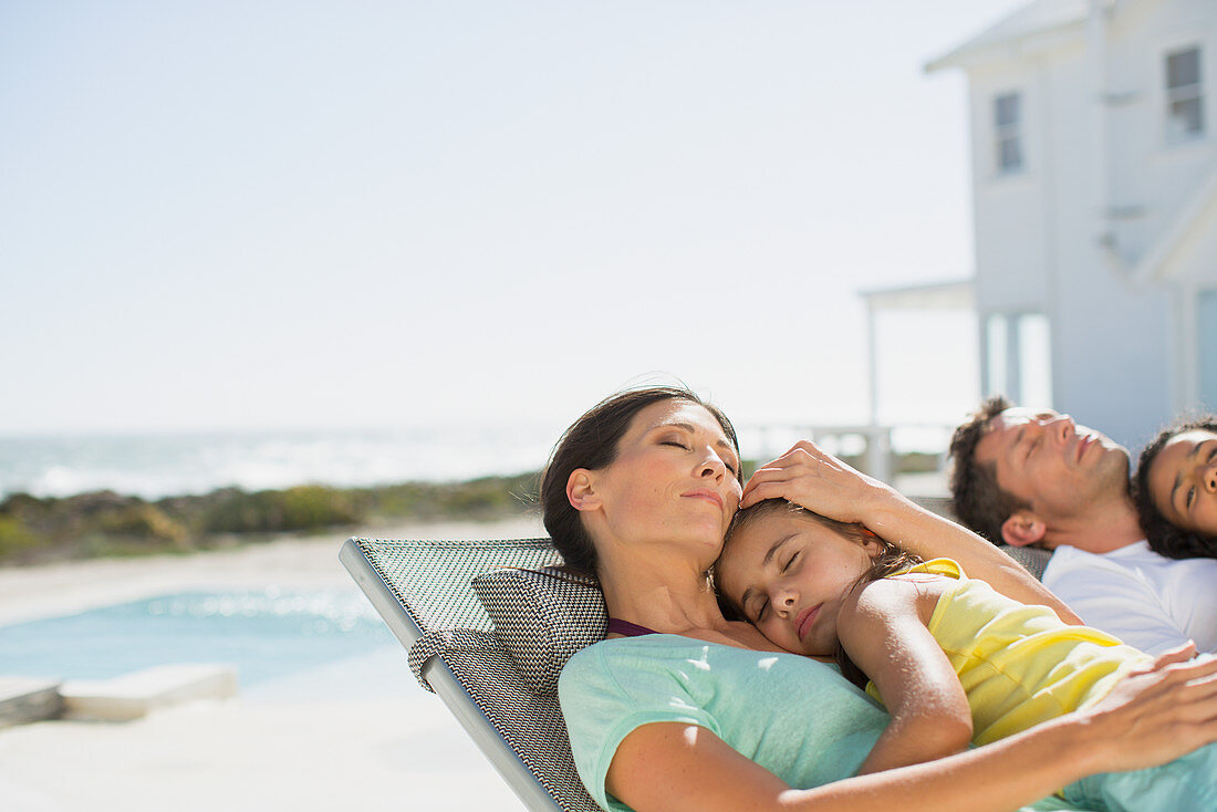 Family sleeping in lounge chairs side