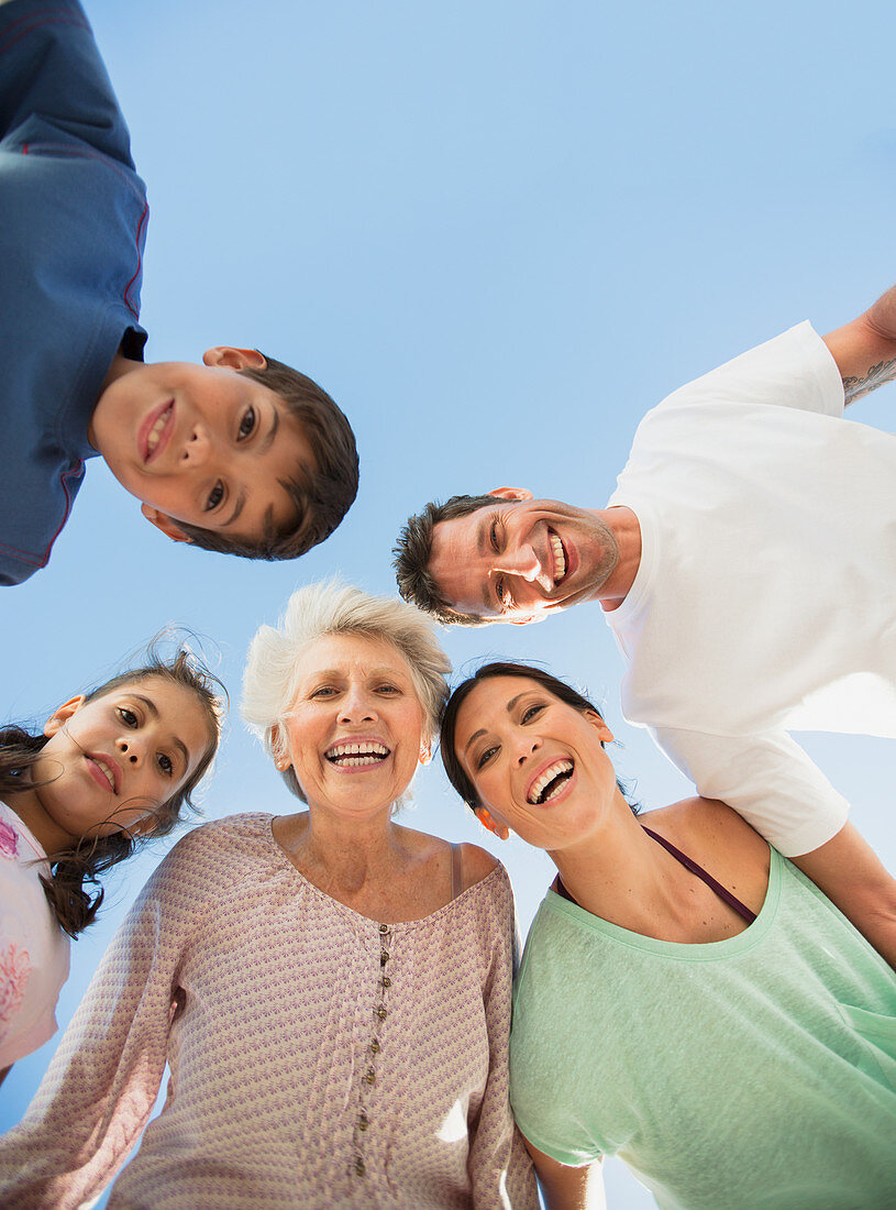 Family smiling in huddle against blue sky