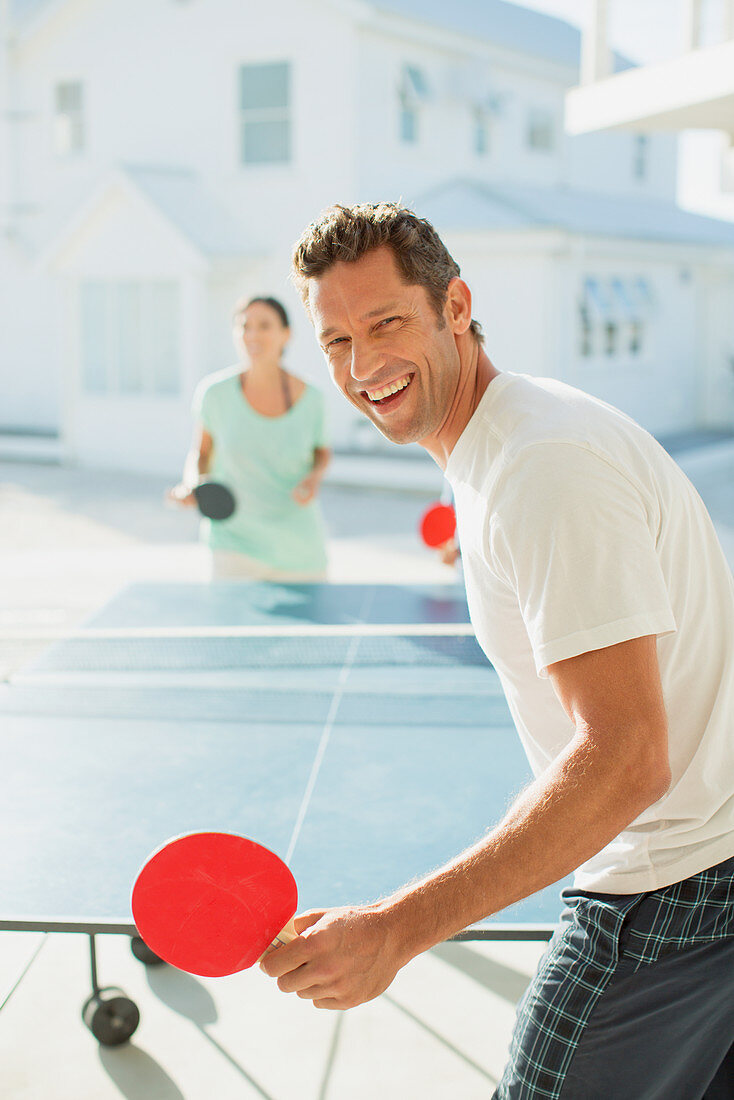 Couple playing table tennis outdoors