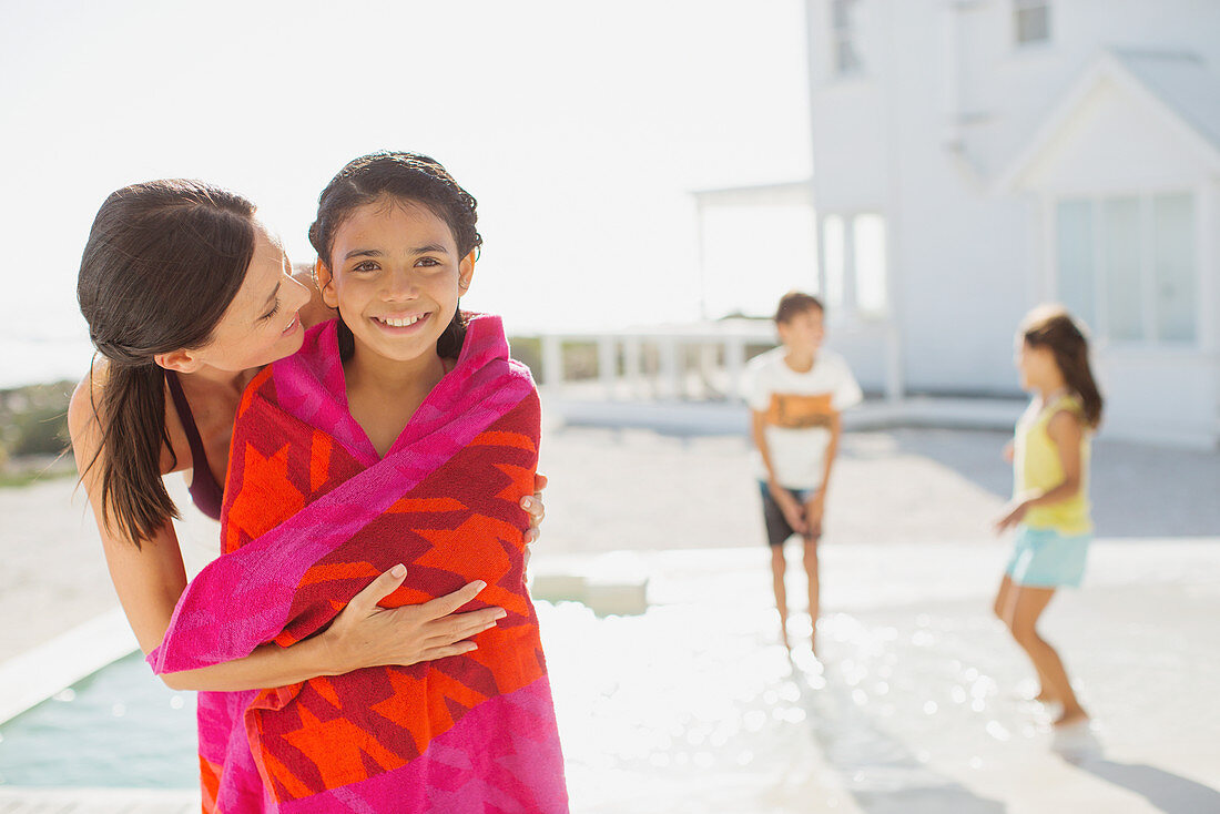 Mother wrapping daughter in towel