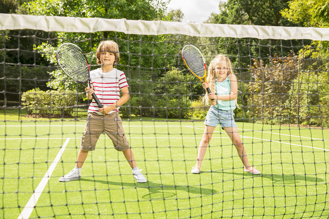 Children playing tennis on grass court