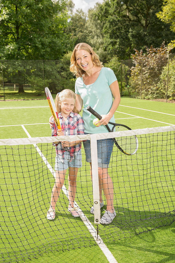 Mother and daughter on grass tennis court