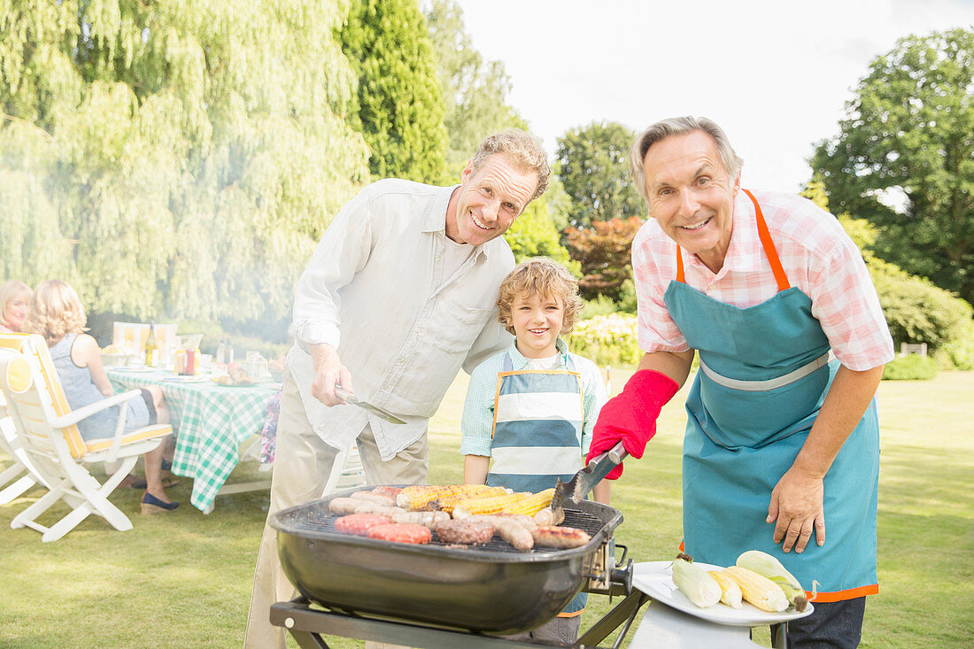 Men grilling meat and corn at barbecue