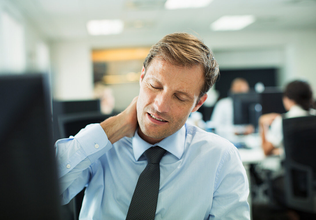 Businessman rubbing his neck in office