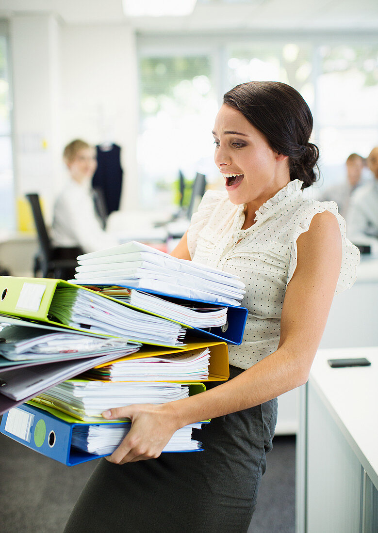Businesswoman carrying folders in office