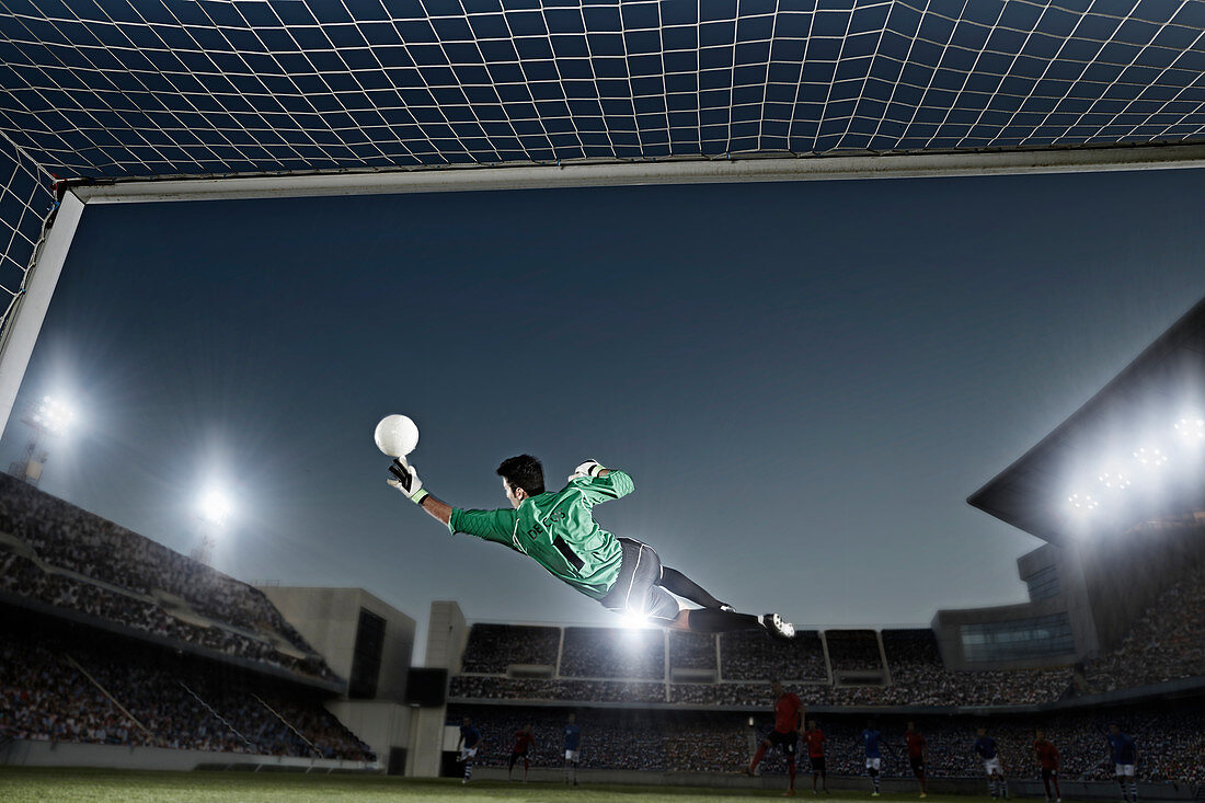 Goalie jumping for ball in soccer net