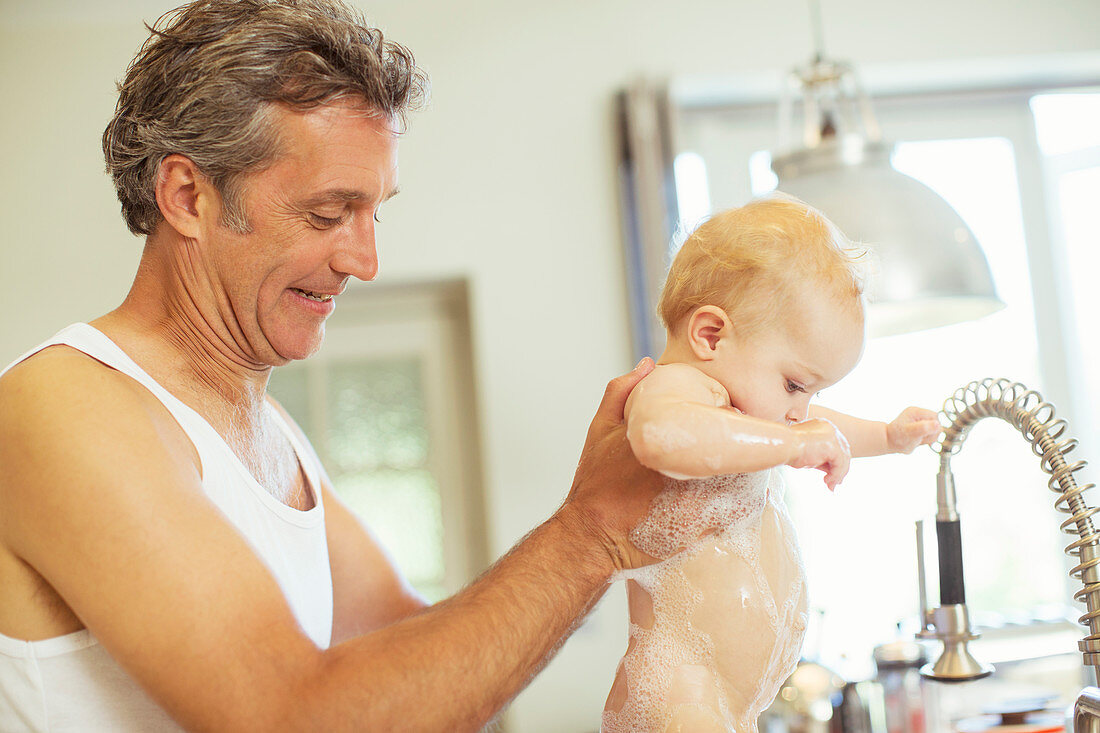 Father washing baby in kitchen sink