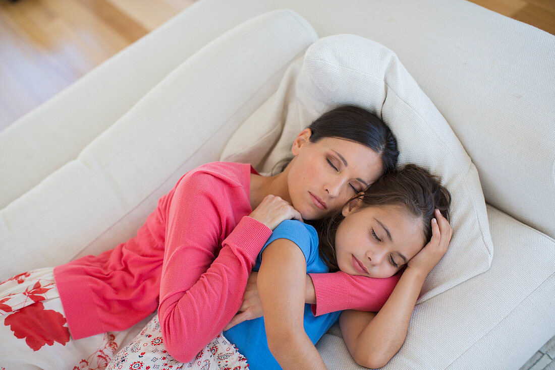 Mother and daughter napping on sofa