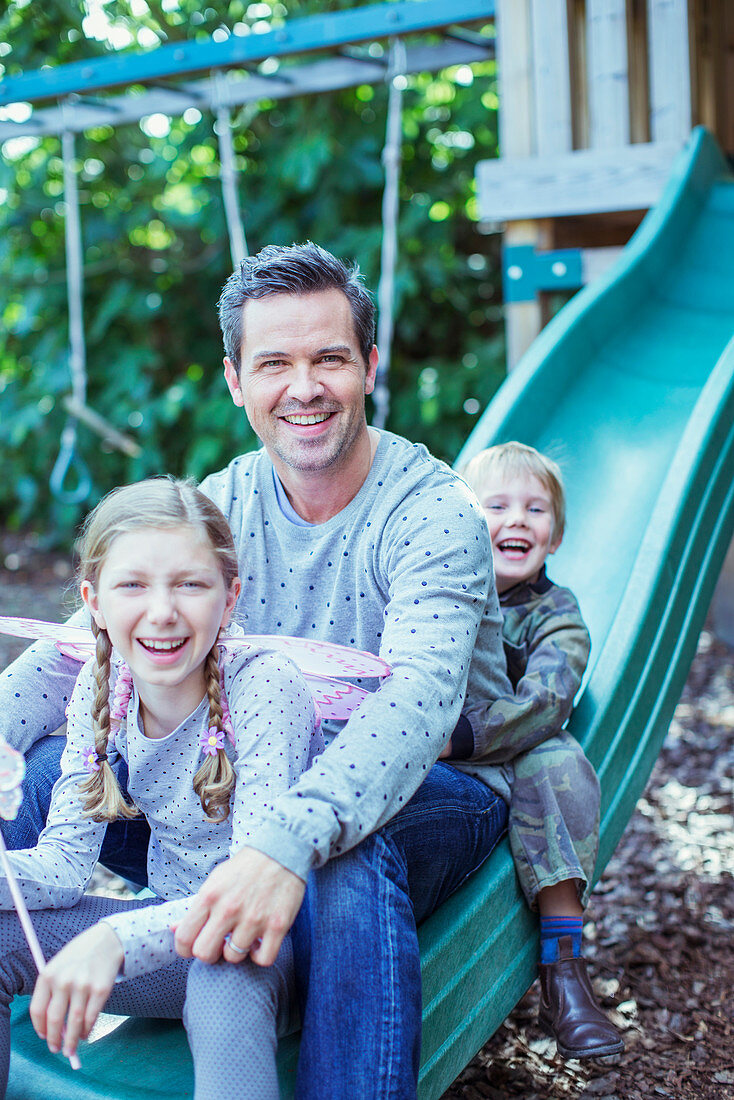 Father and children sitting on slide
