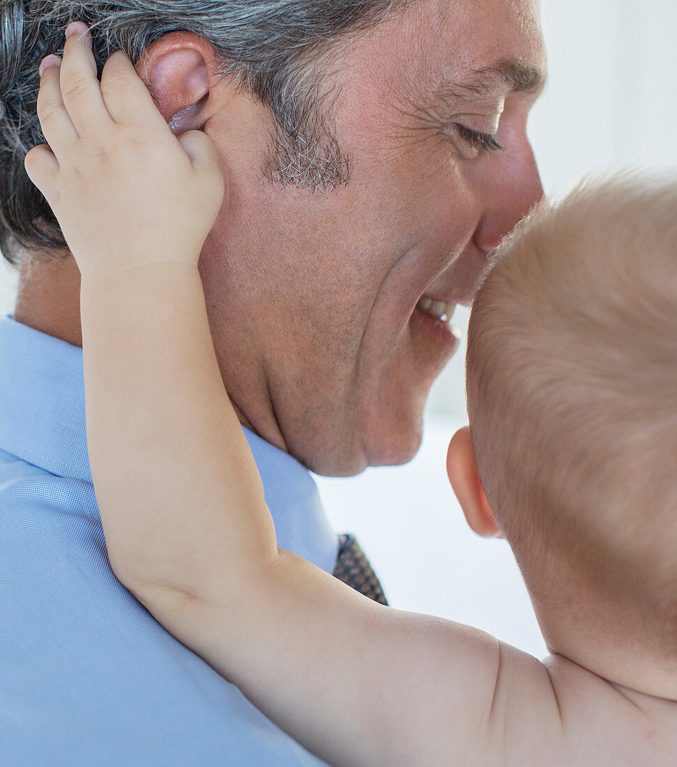 Close up of baby grabbing father's ear