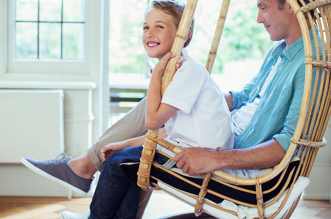 Father and son sitting in wicker chair
