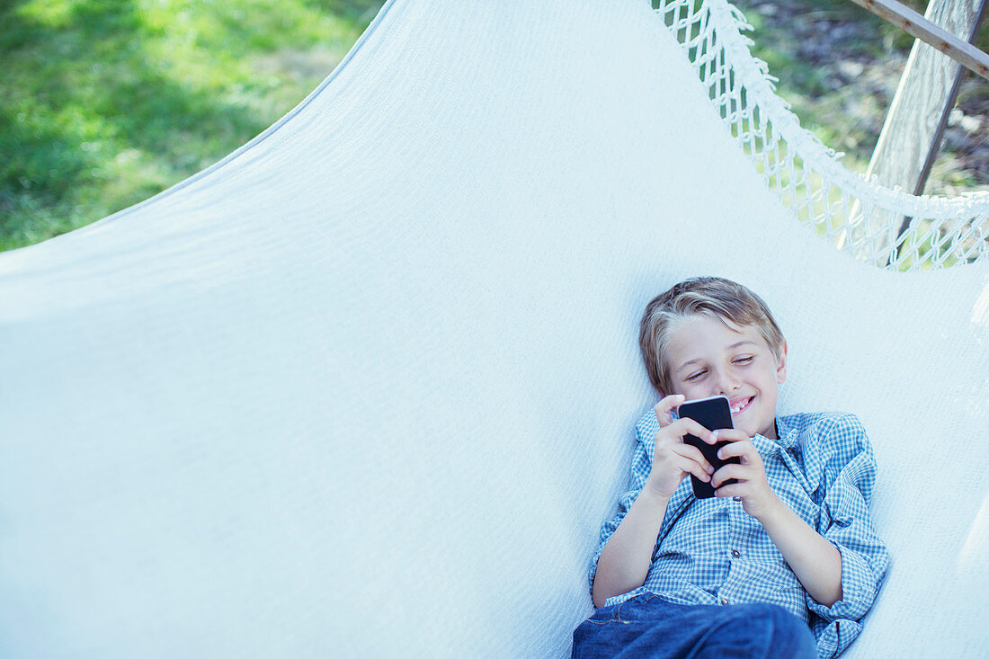 Boy using cell phone in hammock