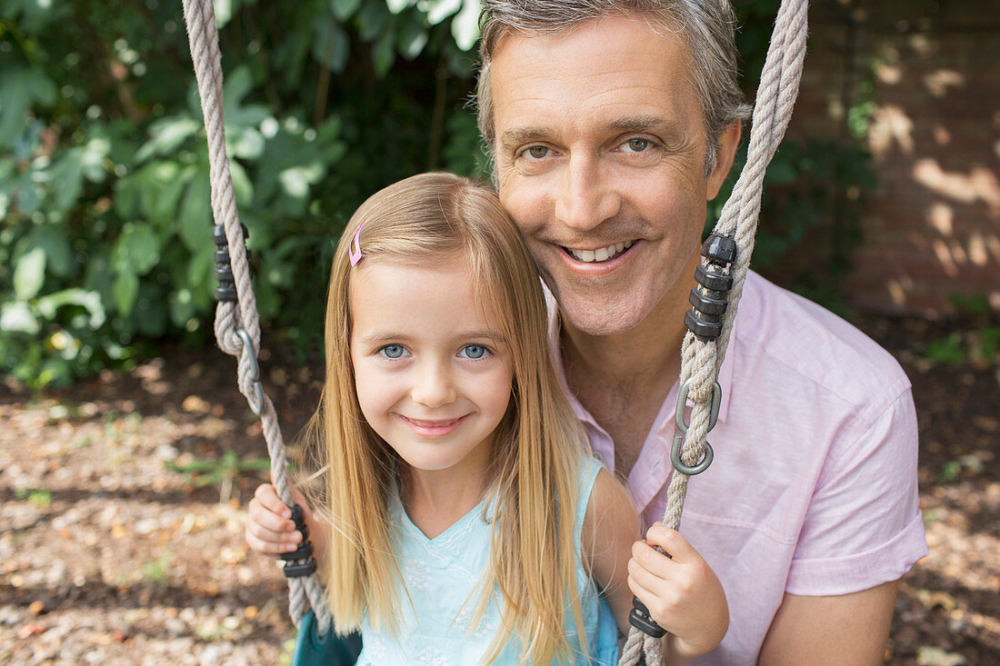 Father pushing daughter on swing