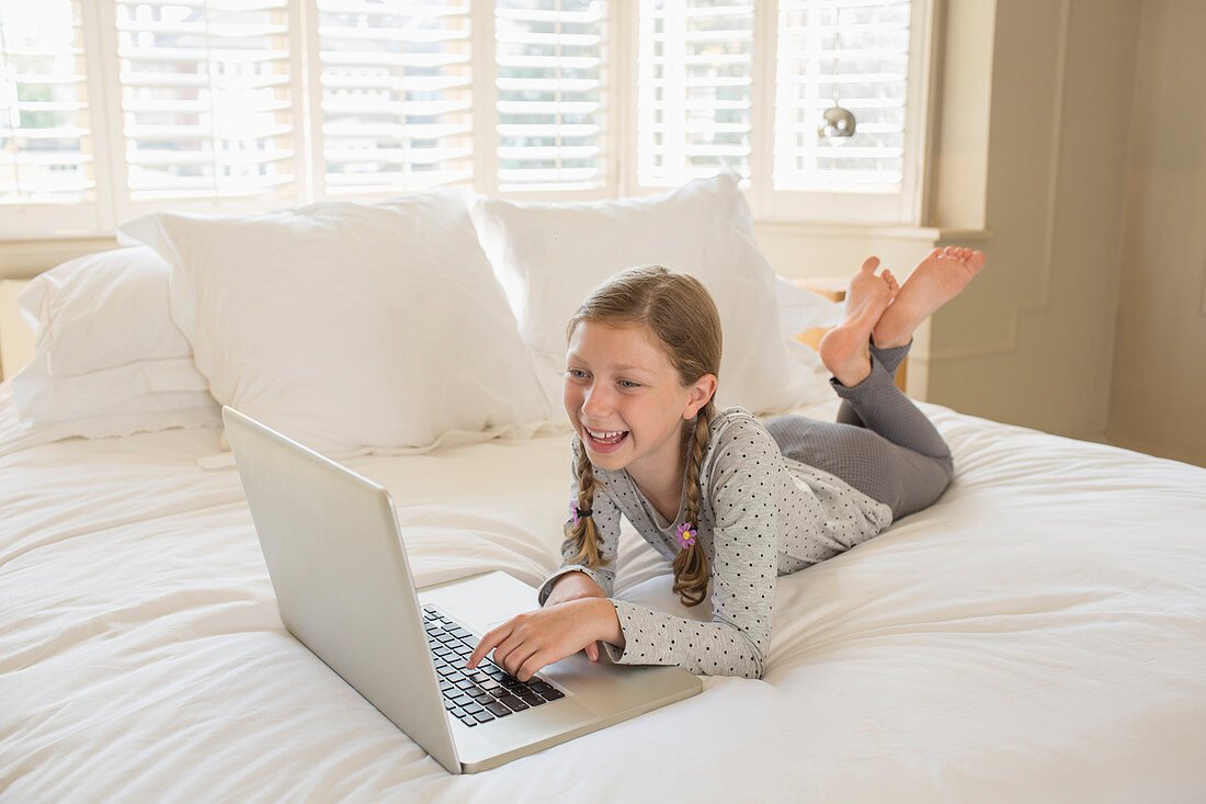 Girl using laptop on bed