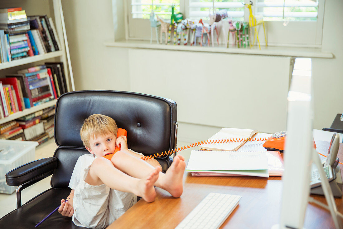 Boy talking on phone in home office