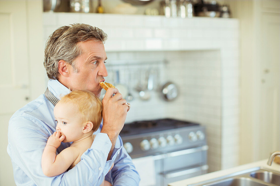 Father holding baby and eating breakfast
