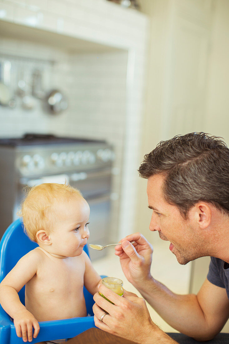 Father feeding baby in high chair