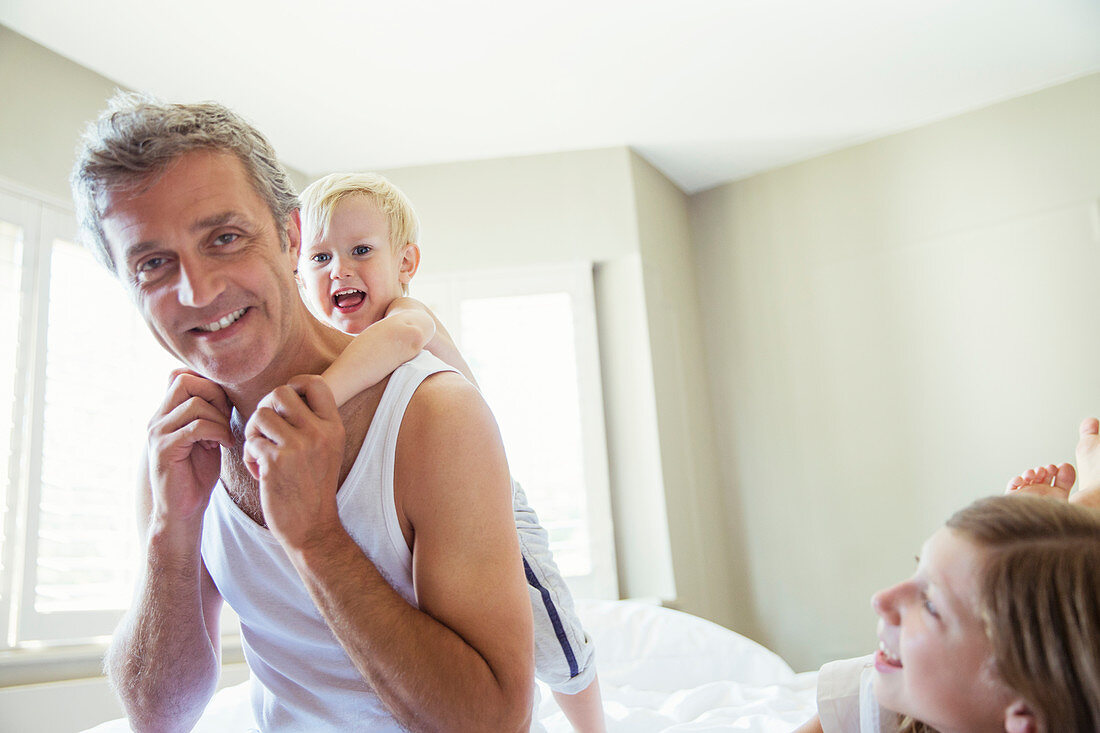 Father and children playing on bed