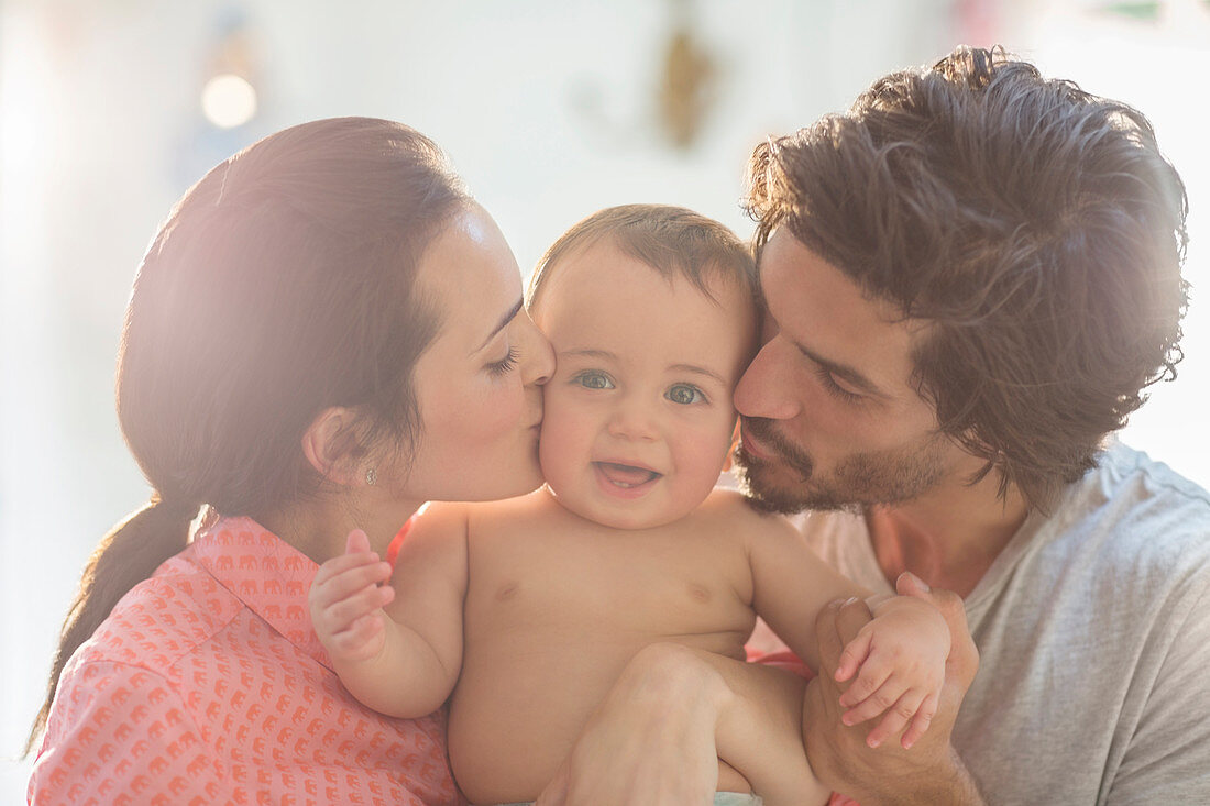 Parents kissing baby boy's cheeks