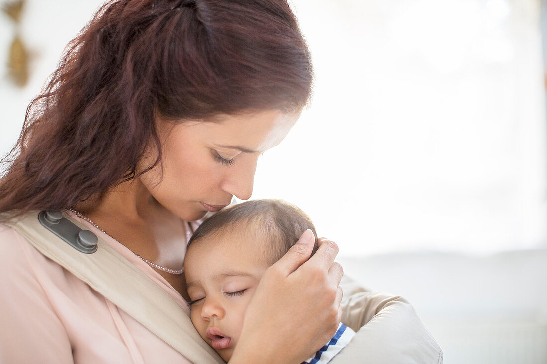 Mother kissing sleeping baby girl