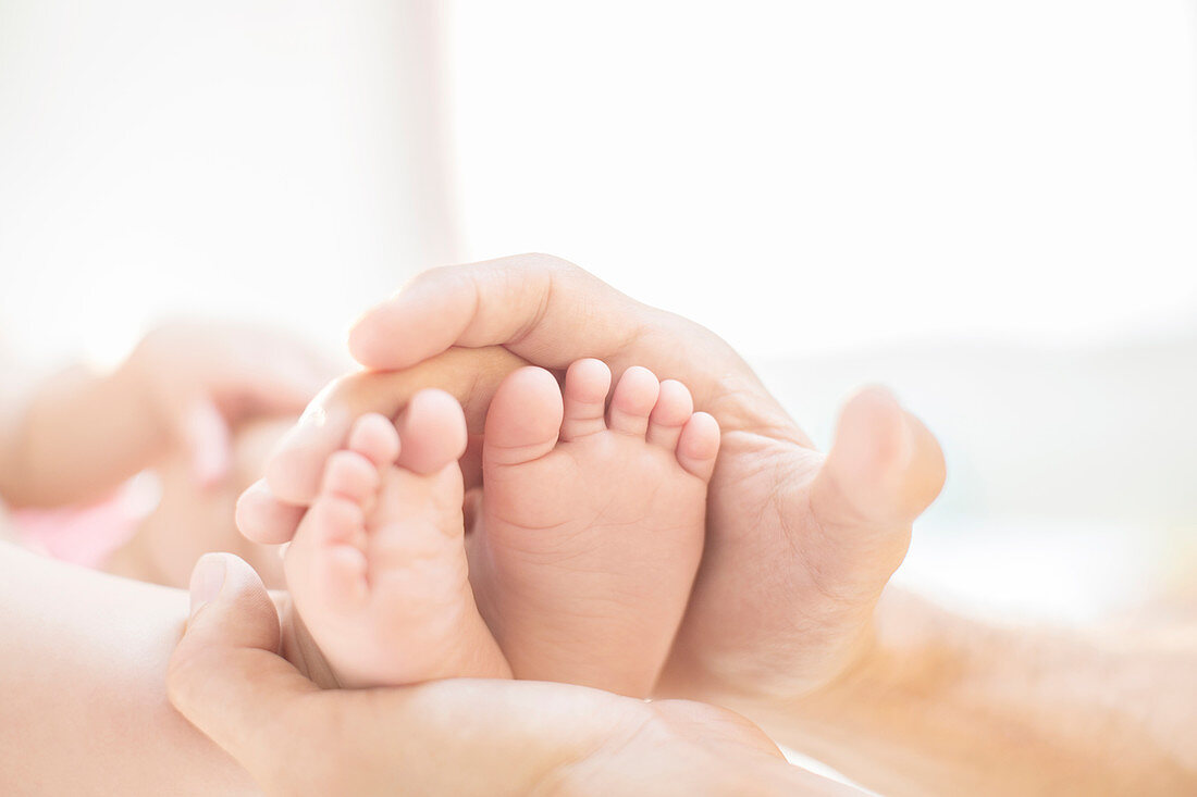 Father cradling baby boy's feet