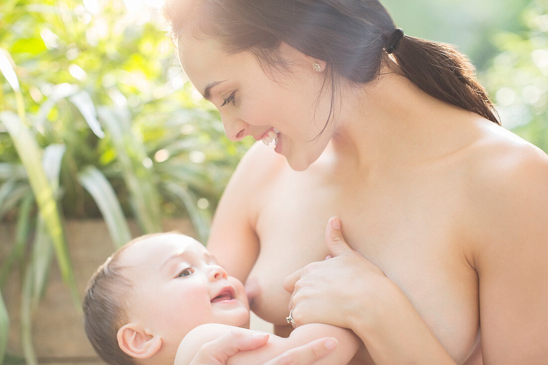 Mother breast-feeding baby boy outdoors